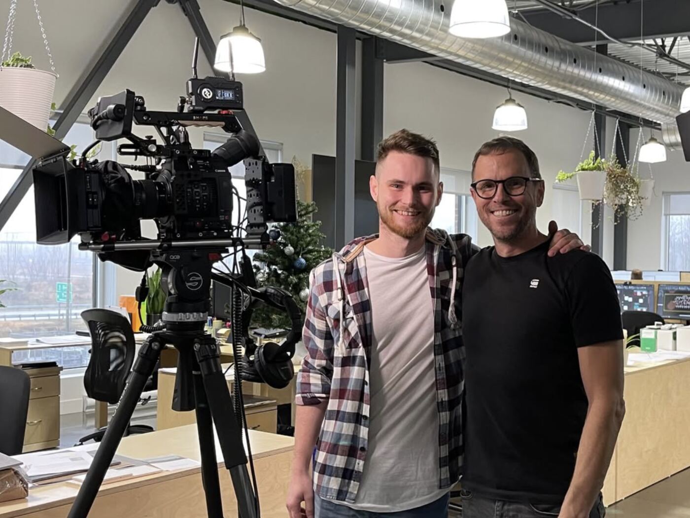 L’équipe de DB Promédia au studio, à côté d’une caméra de cinéma sur trépied.